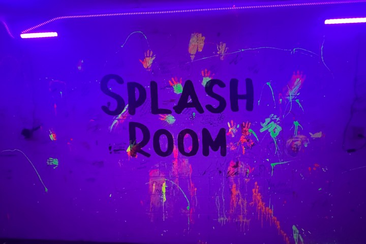 UV-lit wall with 'Splash Room' and colorful paint splatters and handprints.